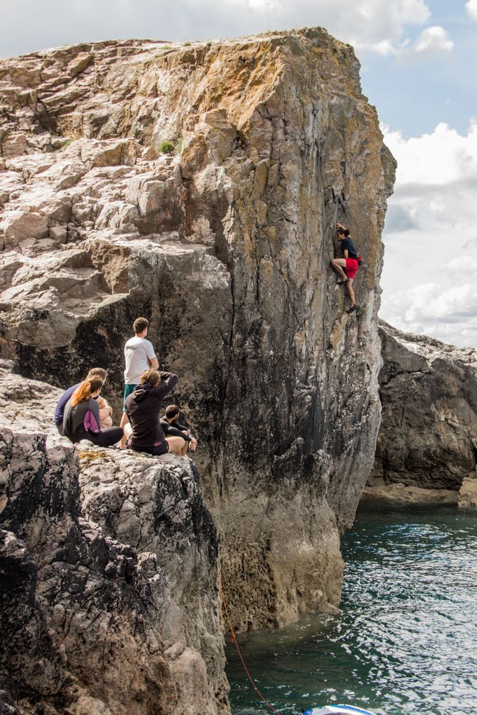 A man deep water soloing as his friends watch
