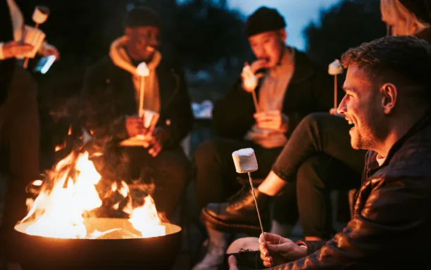 Friends enjoying marshmallow together by the bonfire