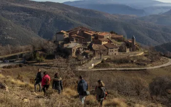 Cinque llac Group of people hiking towards stony village Catalonia Tourism hiking CREDIT ACT autor Christopher Willan Photography