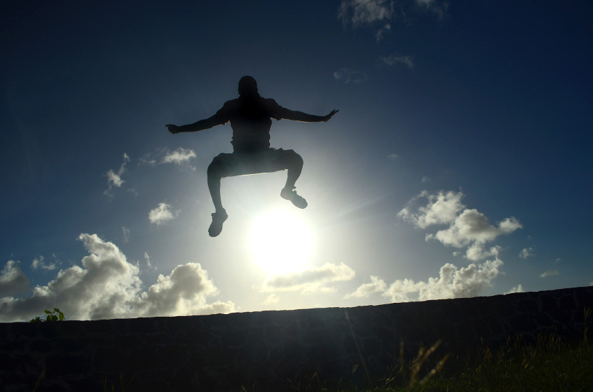 man outdoors jumping against bright sunset