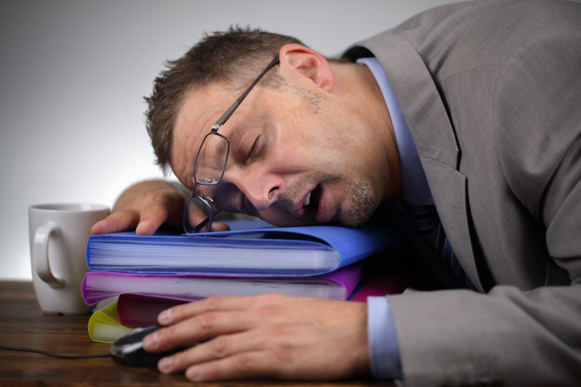Exhausted businessman falling asleep at his office desk