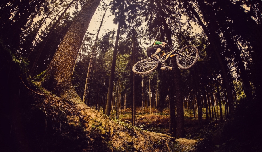 Man on mountain bike jumps high in forest