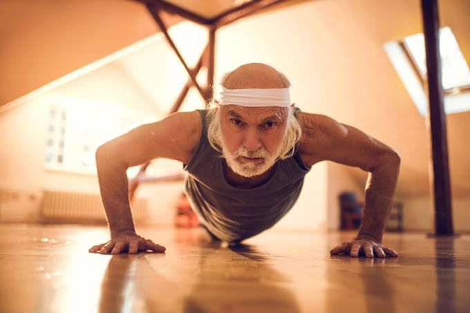 An old man doing press-ups indoors
