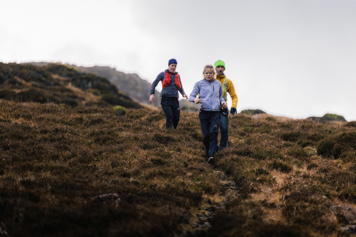 Group running down hill with waterproof gear on - Lake District
