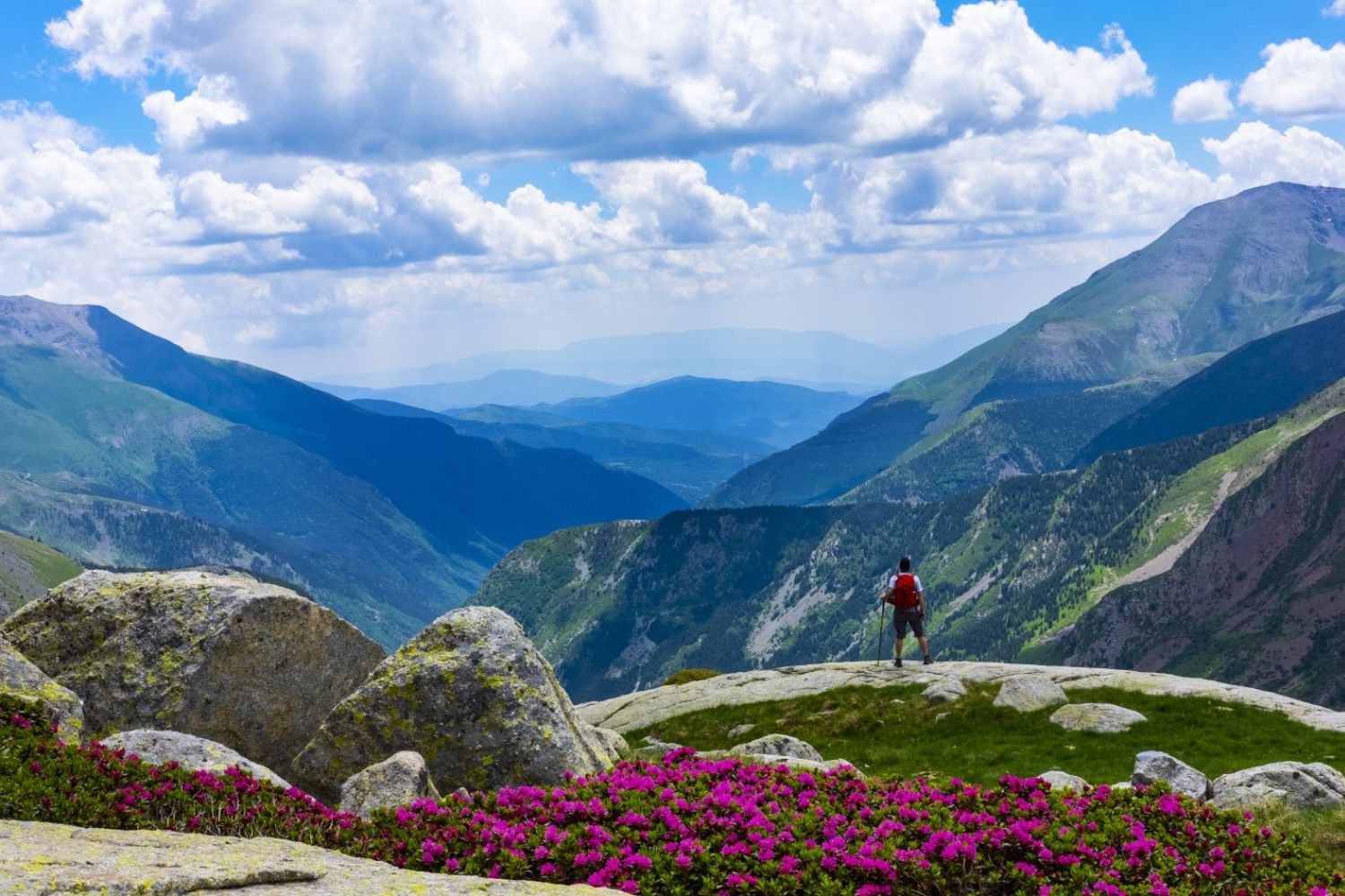 Man standing on rock looking at view of mountains - Aiguestortes i Estany de Sant Maurici National Park, Catalonia