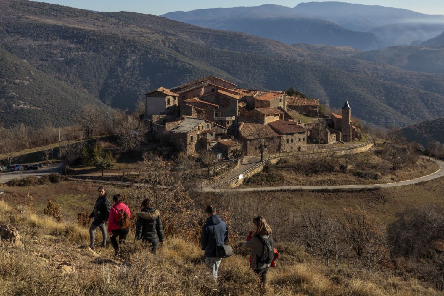 Group of people hiking towards stony village - Cinquè llac, Catalonia