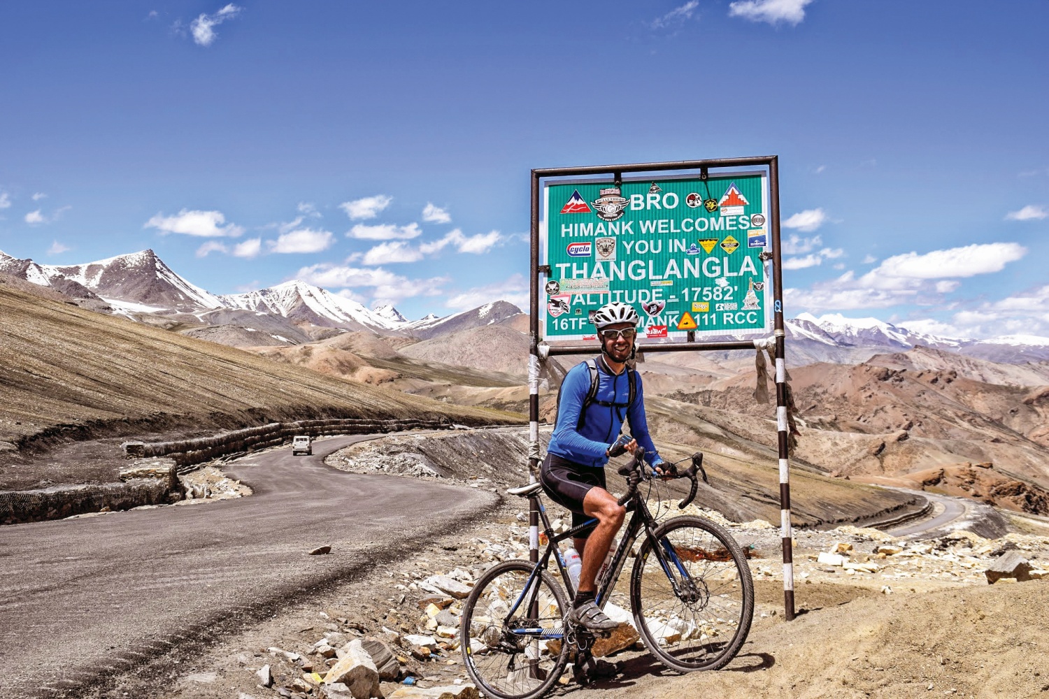 Cyclist stopped by sign with mountains in background, Himalayan Mountains
