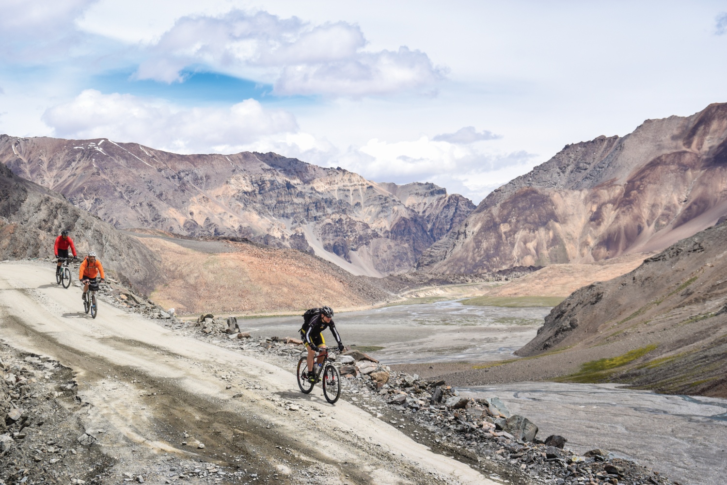 Group of cyclists riding down rocky terrain, Himalayan Mountains