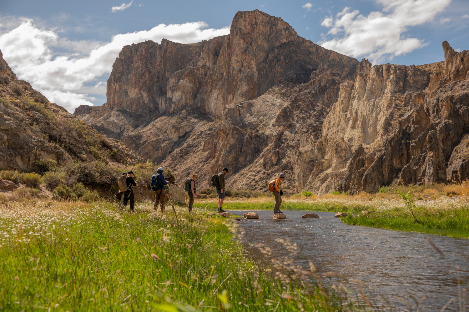 Group of walkers on stepping stones with mountains in background - Trail Huella de Gradin, Patagonia