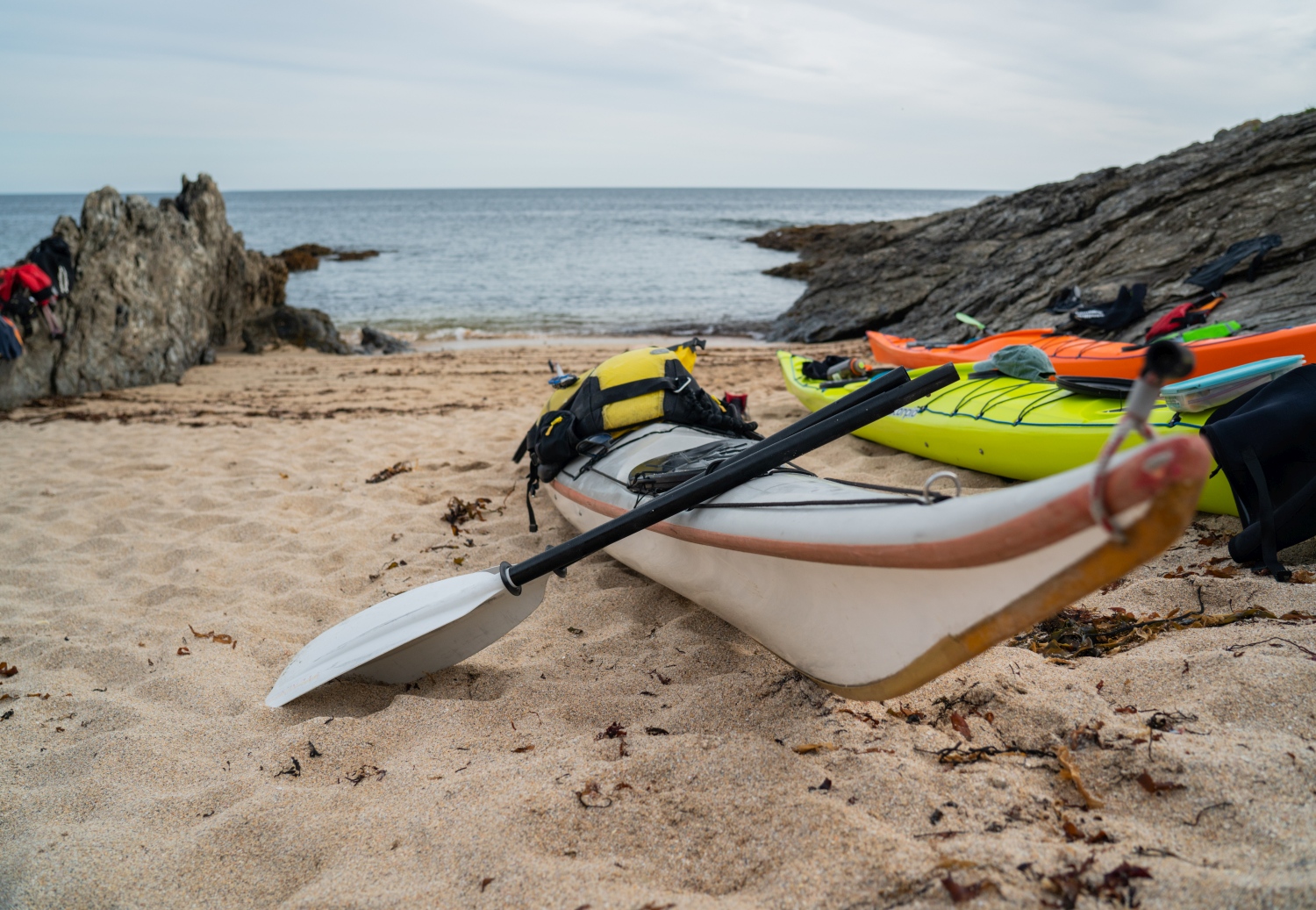 Kayaks parked up on sand next to sea in cove - Brittany, France