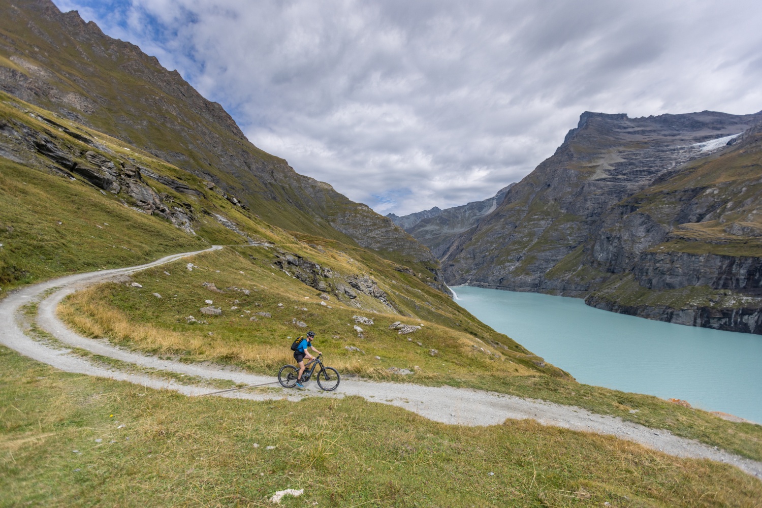 Man cycling along reservoir to Mauvoisin village - Verbier