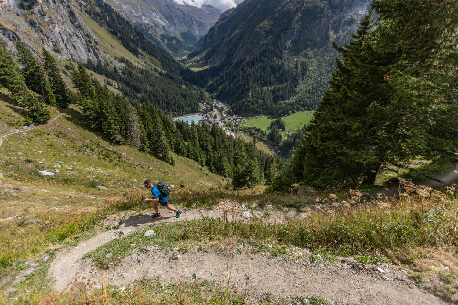 Man running up winding path amongst green mountains - Verbier
