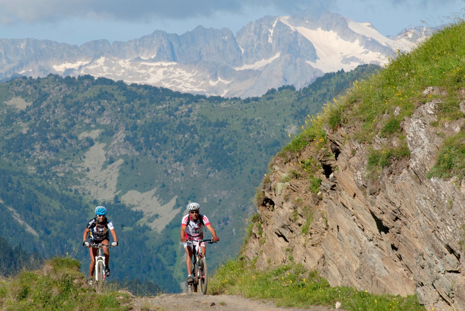 Two cyclists riding along rocky path with mountains in background - Pedals de Foc, Catalonia