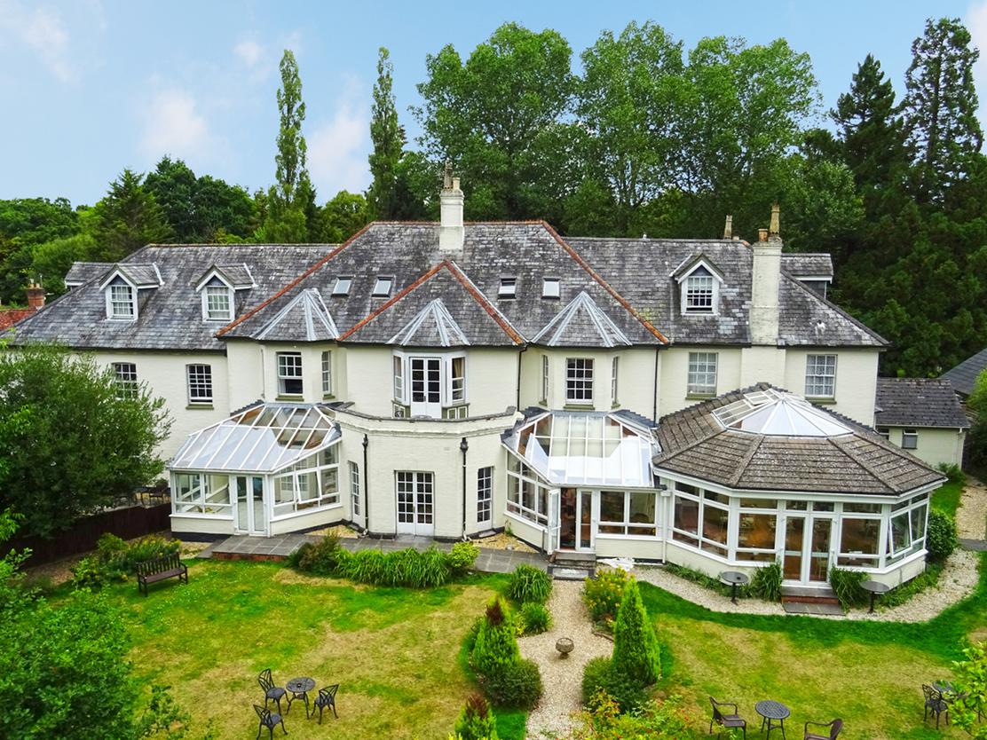 Large white house with bay windows and conservatories_Woodlands Lodge, New Forest