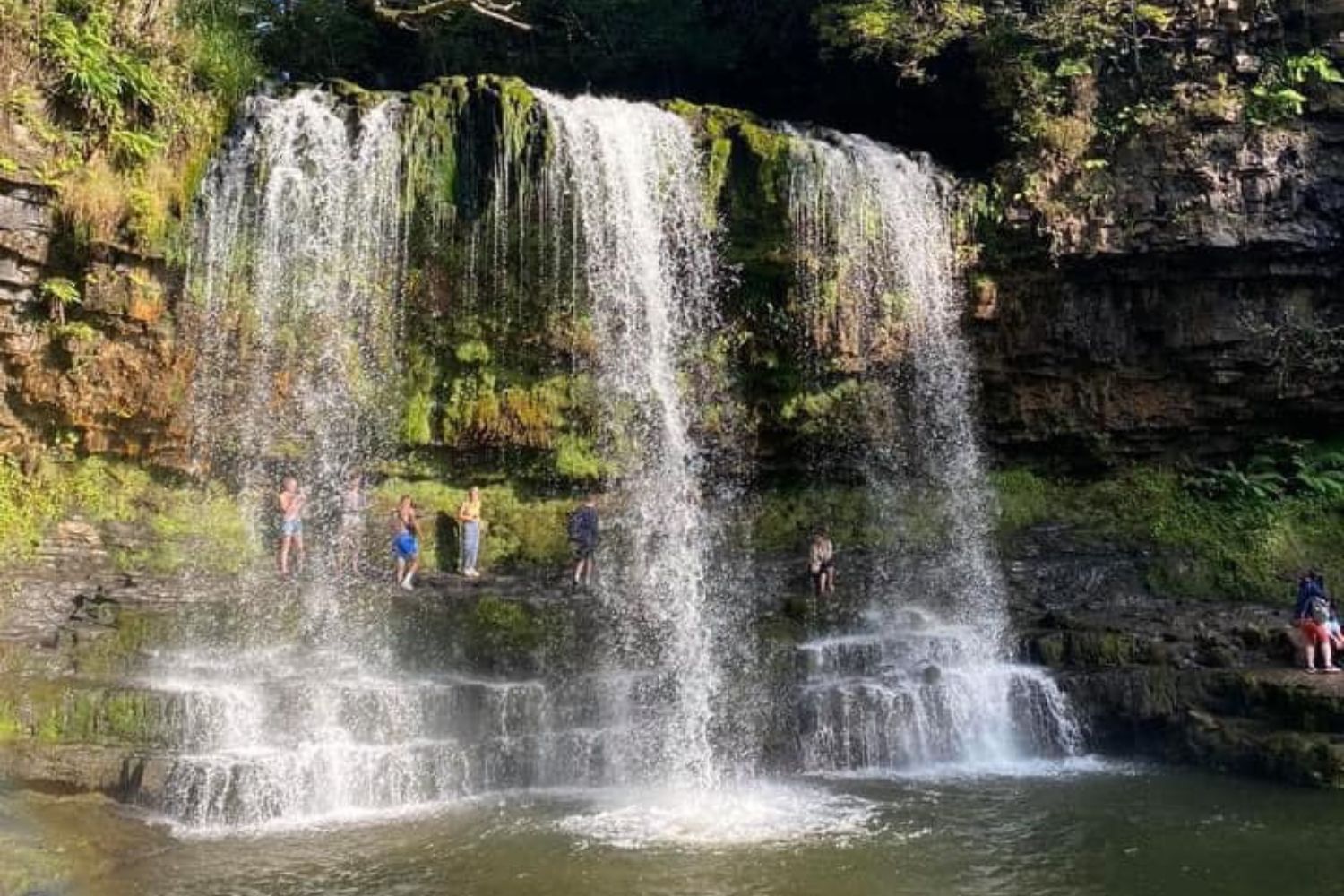 People stood beneath mossy waterfall, Brecon Beacons