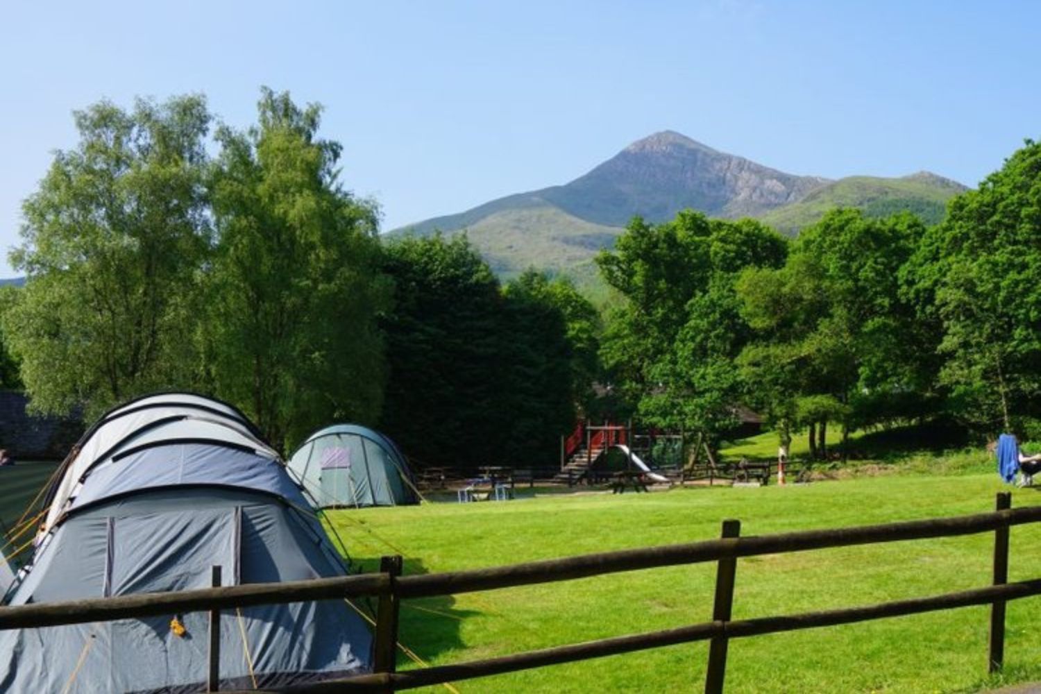 Tents pitched on next to park with mountain in background, Snowdonia
