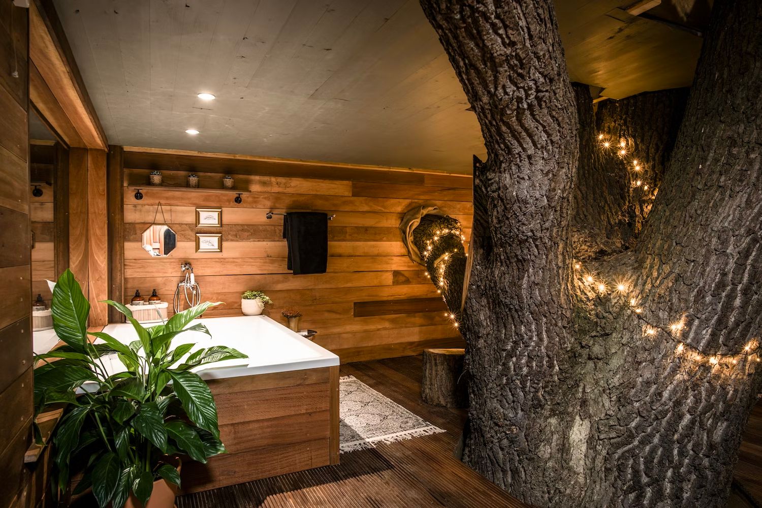 Treehouse bathroom with tree with fairy lights growing through it - The Old Oak Treehouse, Coleman’s Farm, Essex, England