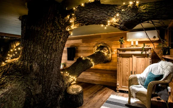 Treehouse living with tree with fairy lights growing through it Top Ten Treehouses CREDIT CoolStays